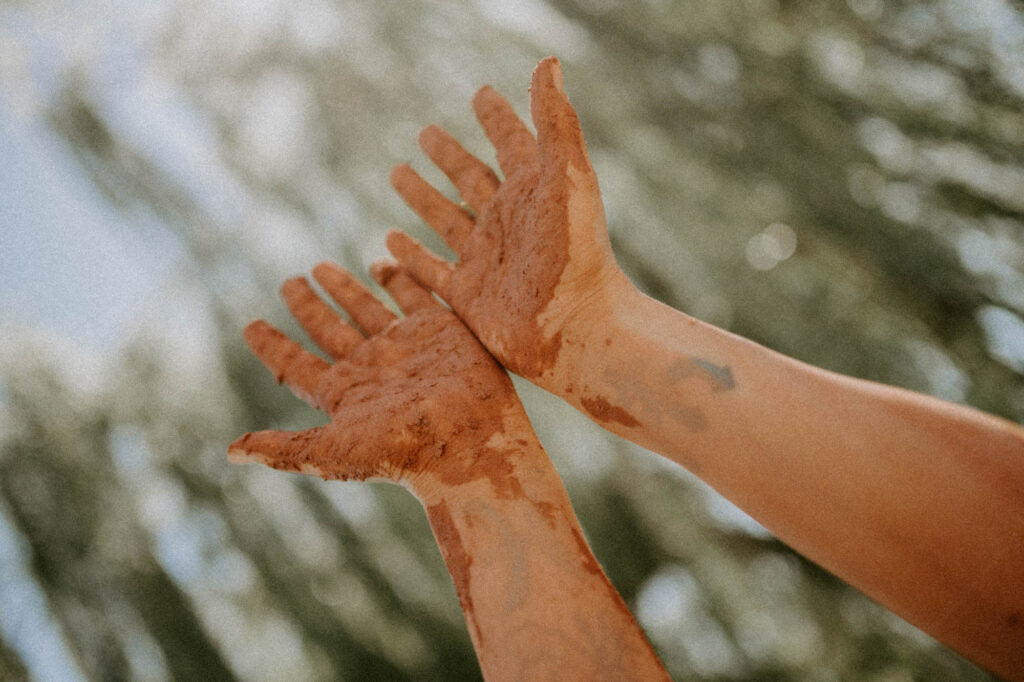 hand in the air covered in clay